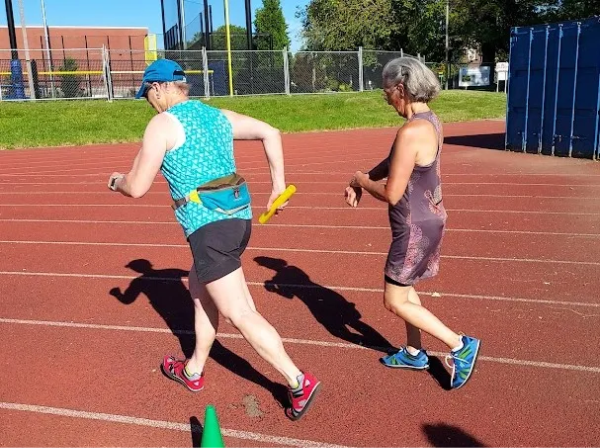 walker handing the baton to her teammate.